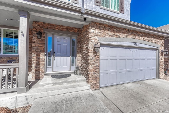 doorway to property featuring a garage, stone siding, and driveway