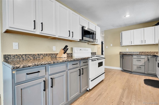 kitchen featuring light hardwood / wood-style flooring, gray cabinets, white range with electric cooktop, dark stone counters, and white cabinets