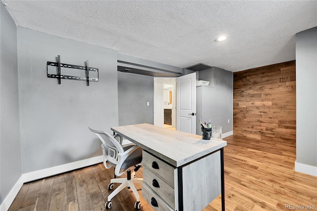 office space featuring light wood-type flooring, a textured ceiling, and wood walls