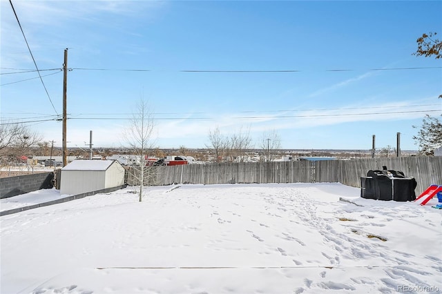 snowy yard featuring a storage unit