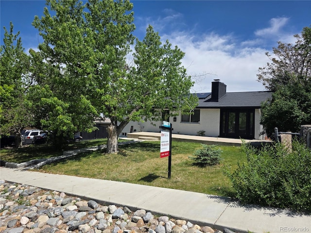 9040 Yucca Way, Thornton, CO 80229 - view of front of property with solar panels, a front lawn, and a chimney