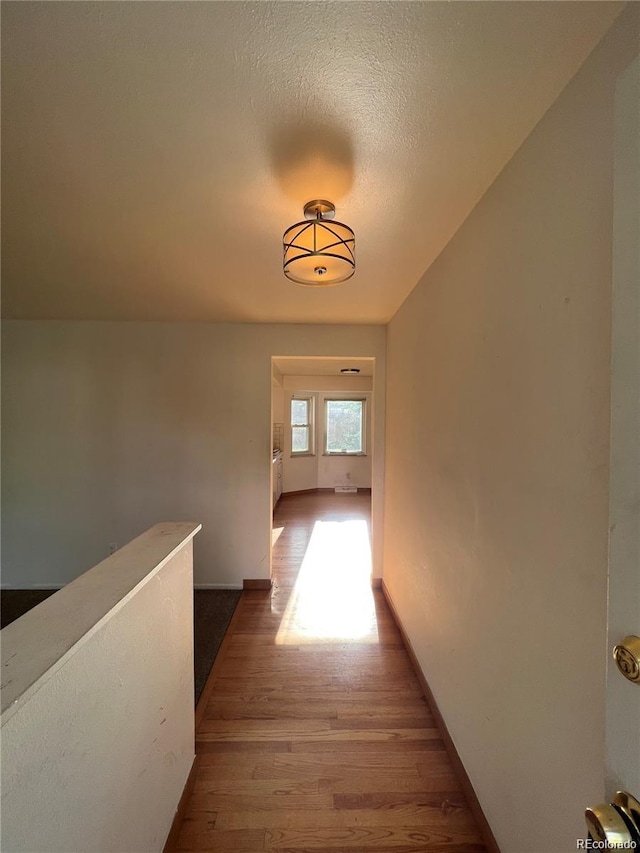 hall with wood-type flooring and a textured ceiling