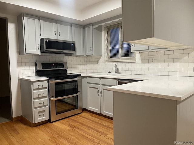 kitchen with decorative backsplash, light stone countertops, stainless steel appliances, sink, and light hardwood / wood-style flooring