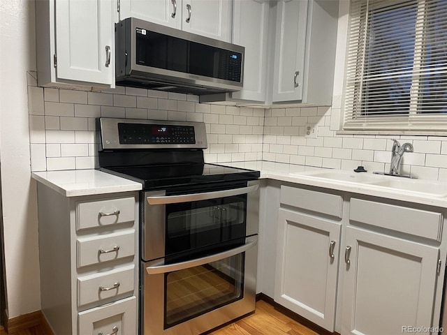 kitchen featuring tasteful backsplash, sink, white cabinets, and stainless steel appliances