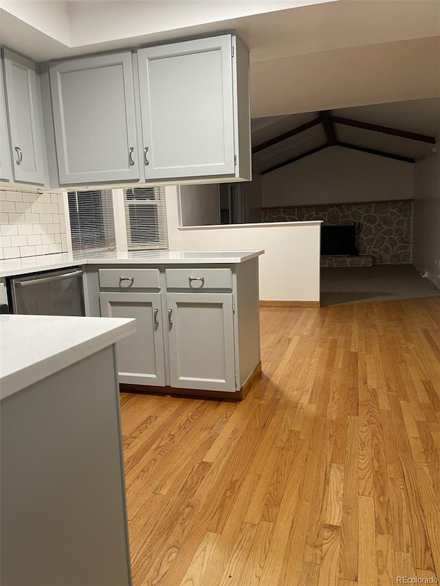 kitchen with stainless steel dishwasher, decorative backsplash, and light hardwood / wood-style floors