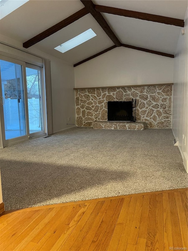 unfurnished living room featuring vaulted ceiling with skylight and a fireplace