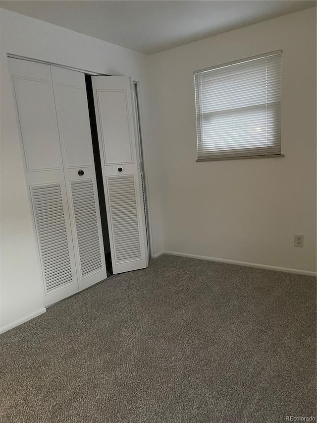 unfurnished bedroom with dark carpet and a closet