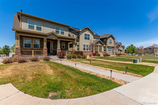 craftsman-style house with stone siding, a porch, a residential view, and a front lawn