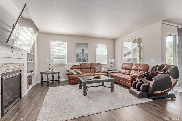 living room with plenty of natural light, dark wood finished floors, a brick fireplace, and a textured ceiling