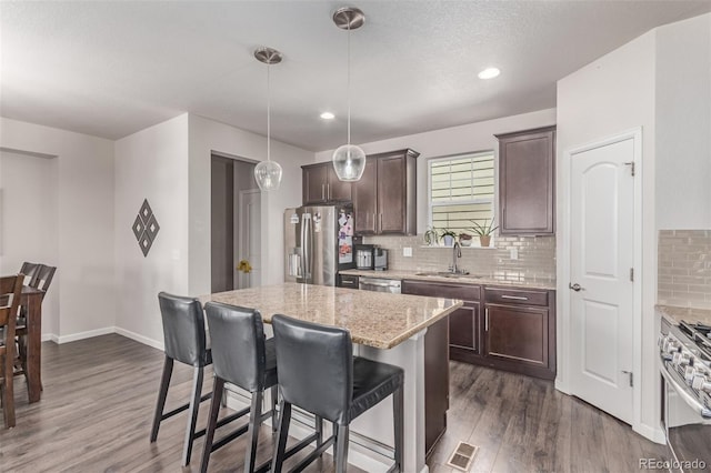 kitchen with stainless steel appliances, dark wood-style flooring, dark brown cabinets, backsplash, and recessed lighting