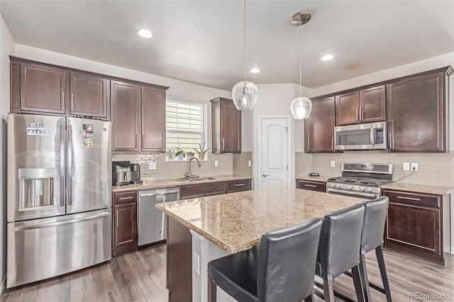 kitchen with stainless steel appliances, a sink, dark brown cabinetry, and recessed lighting