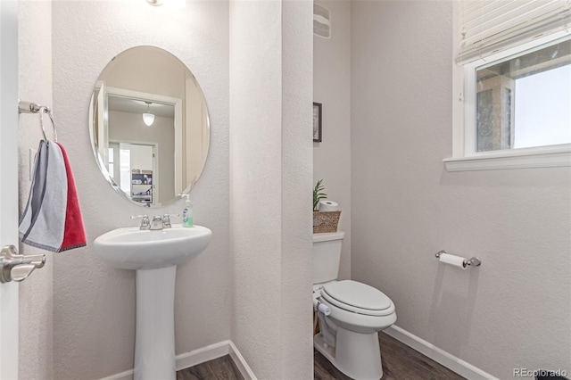 bathroom featuring wood finished floors, toilet, healthy amount of natural light, and baseboards