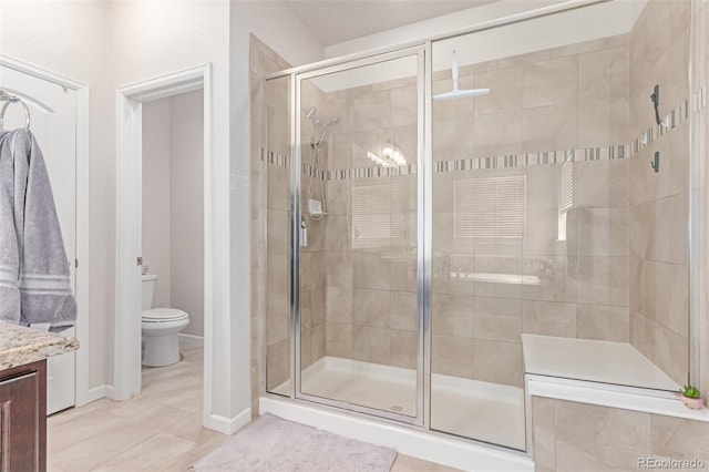 full bath featuring a stall shower, toilet, vanity, tile patterned flooring, and baseboards