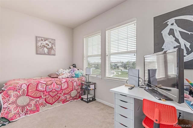 bedroom with multiple windows, light colored carpet, an office area, and baseboards