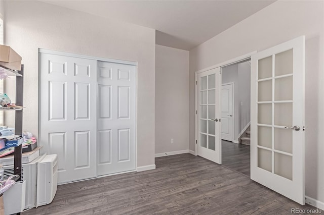 unfurnished bedroom featuring french doors, dark wood finished floors, and baseboards
