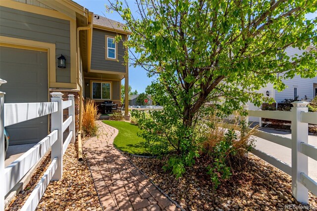 view of yard with fence, a garage, and a porch
