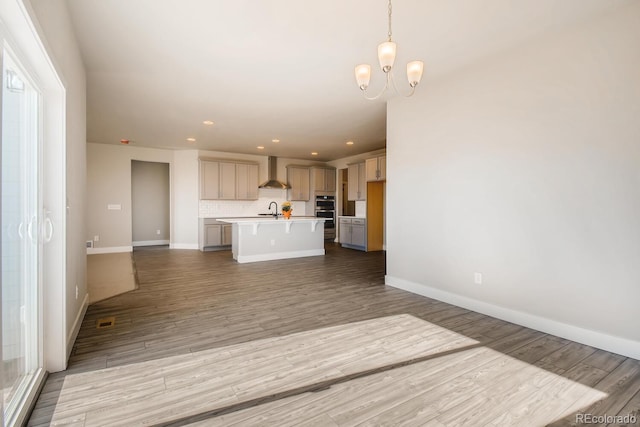 unfurnished living room with wood finished floors, a sink, and a notable chandelier