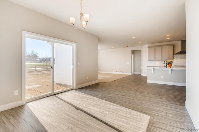 unfurnished living room featuring light wood finished floors, baseboards, and a sink