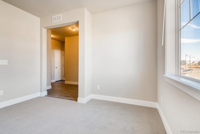 unfurnished room with baseboards, visible vents, and carpet floors