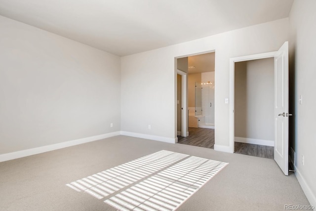unfurnished bedroom featuring baseboards, ensuite bath, and carpet flooring