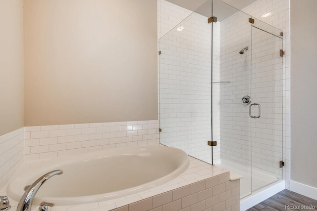 bathroom with a garden tub, wood finished floors, and a shower stall