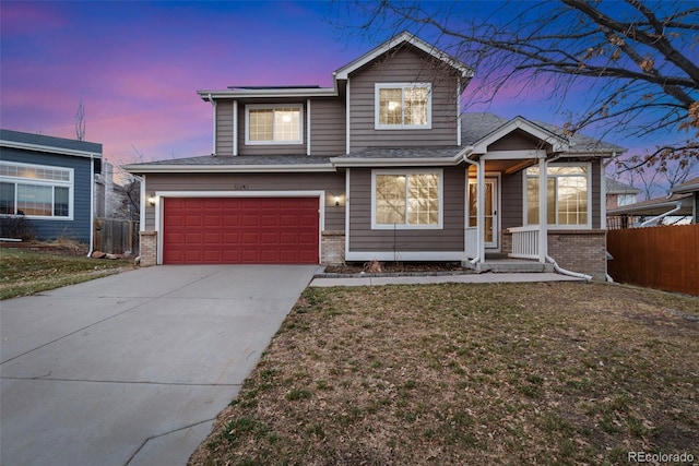 traditional-style home with brick siding, a yard, fence, a garage, and driveway