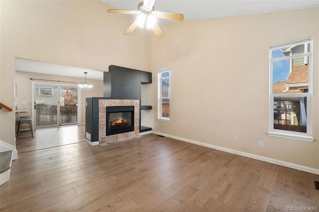 unfurnished living room featuring baseboards, a tiled fireplace, and wood finished floors