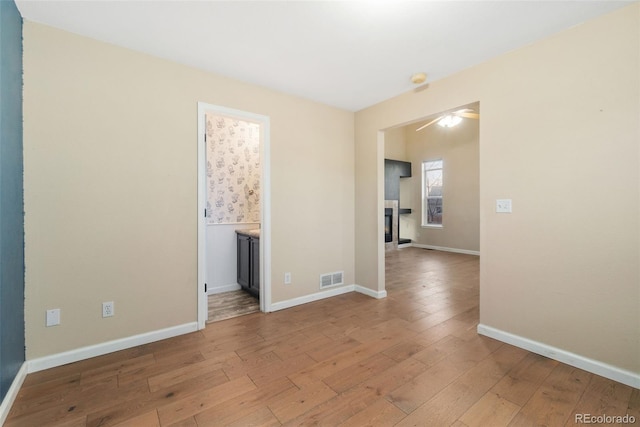 unfurnished room with wood-type flooring, visible vents, and baseboards