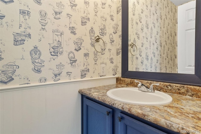 bathroom featuring wainscoting, vanity, and wallpapered walls