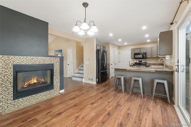 kitchen with stainless steel appliances, light wood-type flooring, a sink, and a peninsula