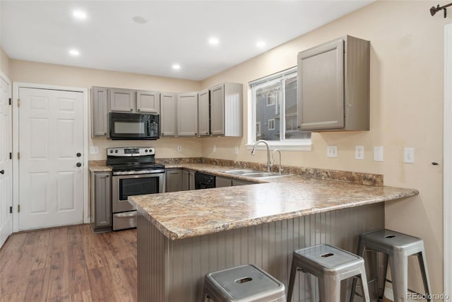 kitchen featuring gray cabinetry, a sink, a peninsula, and black appliances