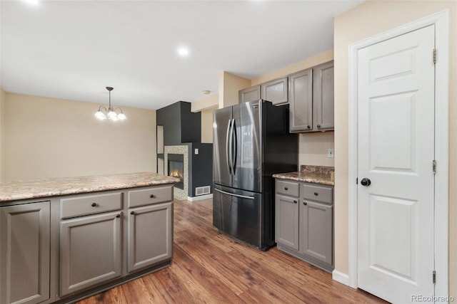 kitchen featuring freestanding refrigerator, gray cabinetry, and wood finished floors