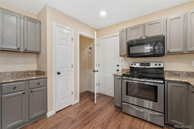 kitchen featuring black microwave, gray cabinetry, dark wood-type flooring, baseboards, and stainless steel range with electric cooktop