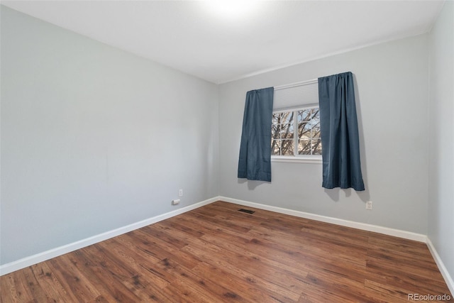 spare room featuring baseboards, visible vents, and wood finished floors