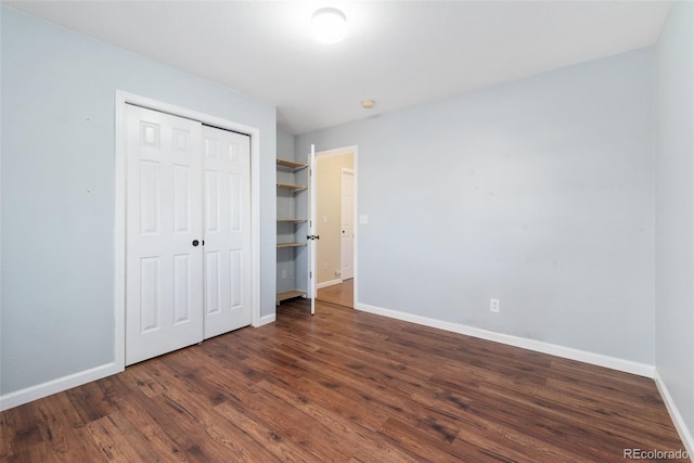 unfurnished bedroom with dark wood-style floors, baseboards, and a closet