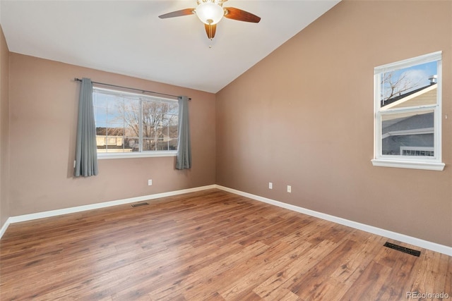 spare room with lofted ceiling, visible vents, and wood finished floors