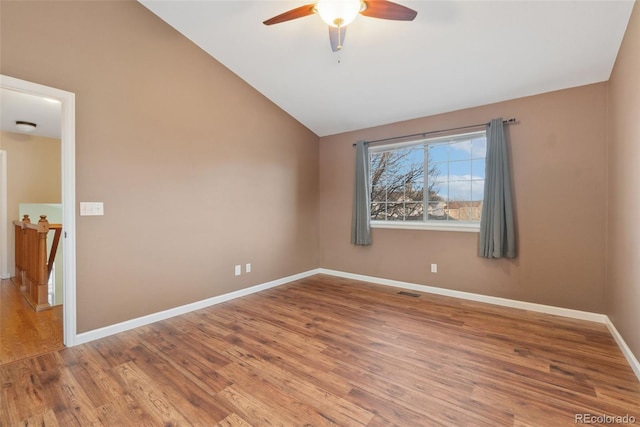 unfurnished room with visible vents, ceiling fan, vaulted ceiling, wood finished floors, and baseboards