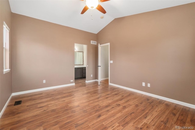 unfurnished bedroom with baseboards, visible vents, lofted ceiling, wood finished floors, and ensuite bathroom