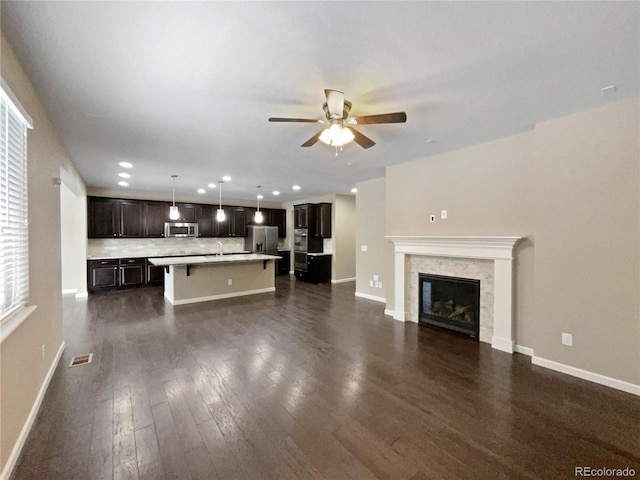 unfurnished living room with ceiling fan, a premium fireplace, and dark hardwood / wood-style flooring