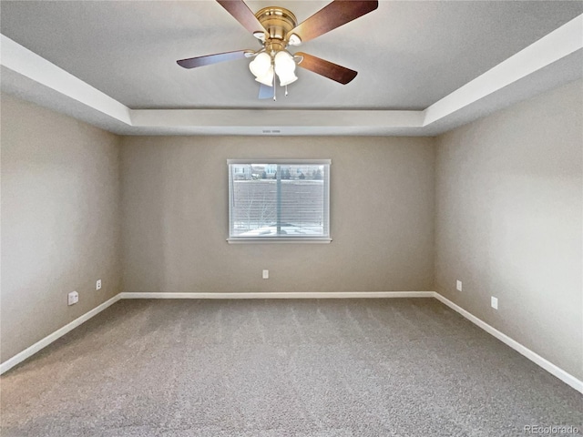 carpeted empty room with ceiling fan and a tray ceiling