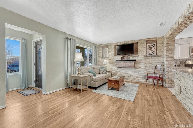 living room featuring a wealth of natural light, a textured ceiling, and light hardwood / wood-style flooring