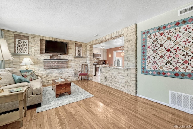 living room featuring hardwood / wood-style floors, sink, and a textured ceiling