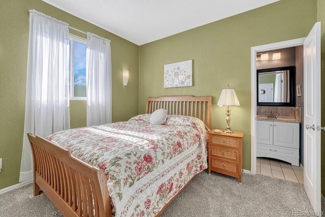 bedroom with light colored carpet, ensuite bathroom, and sink