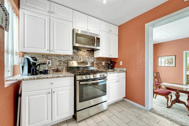 kitchen featuring appliances with stainless steel finishes, a textured ceiling, decorative backsplash, and white cabinets