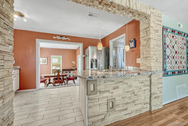 kitchen featuring hanging light fixtures, sink, kitchen peninsula, and stainless steel fridge with ice dispenser