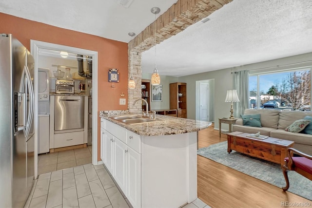 kitchen featuring pendant lighting, white cabinetry, sink, stainless steel refrigerator with ice dispenser, and light hardwood / wood-style flooring