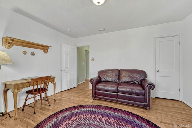 living room with a textured ceiling and light hardwood / wood-style floors