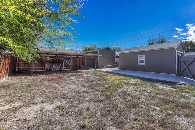 back of house featuring a patio, a yard, and a storage unit