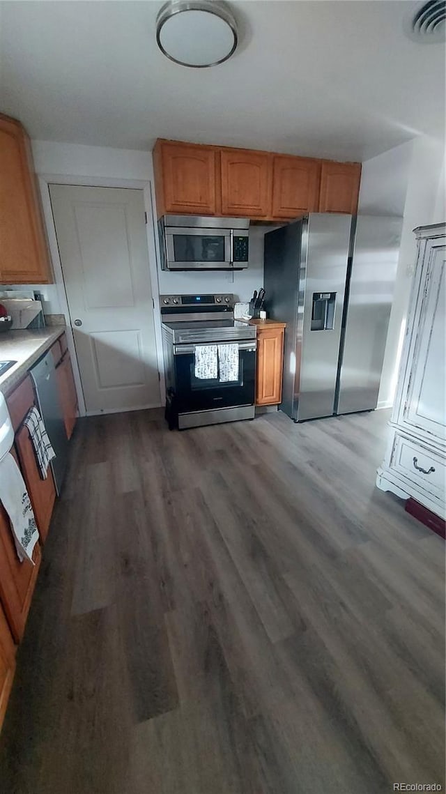 kitchen featuring brown cabinetry, visible vents, appliances with stainless steel finishes, and dark wood-style flooring