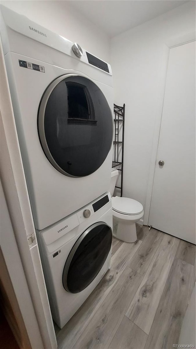 laundry room with laundry area, light wood-style flooring, and stacked washer / drying machine